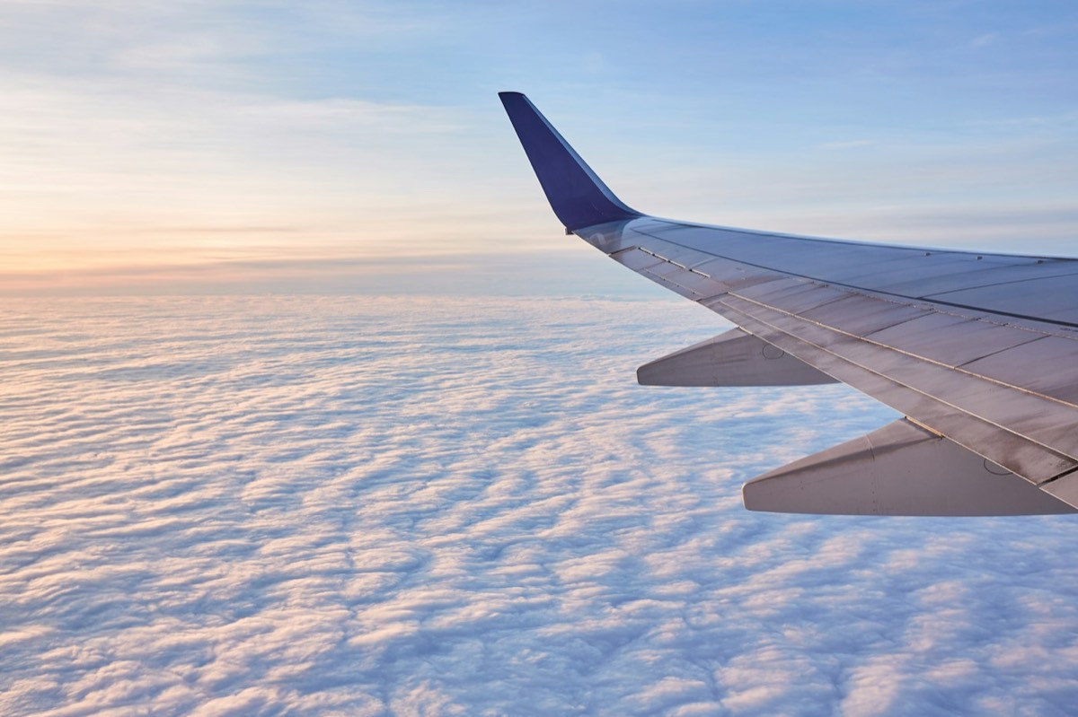 Aircraft wing above the clouds at sunrise